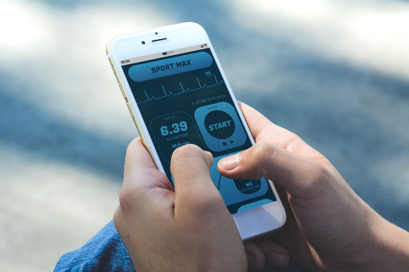 Person using fitness app on smartphone outdoors.